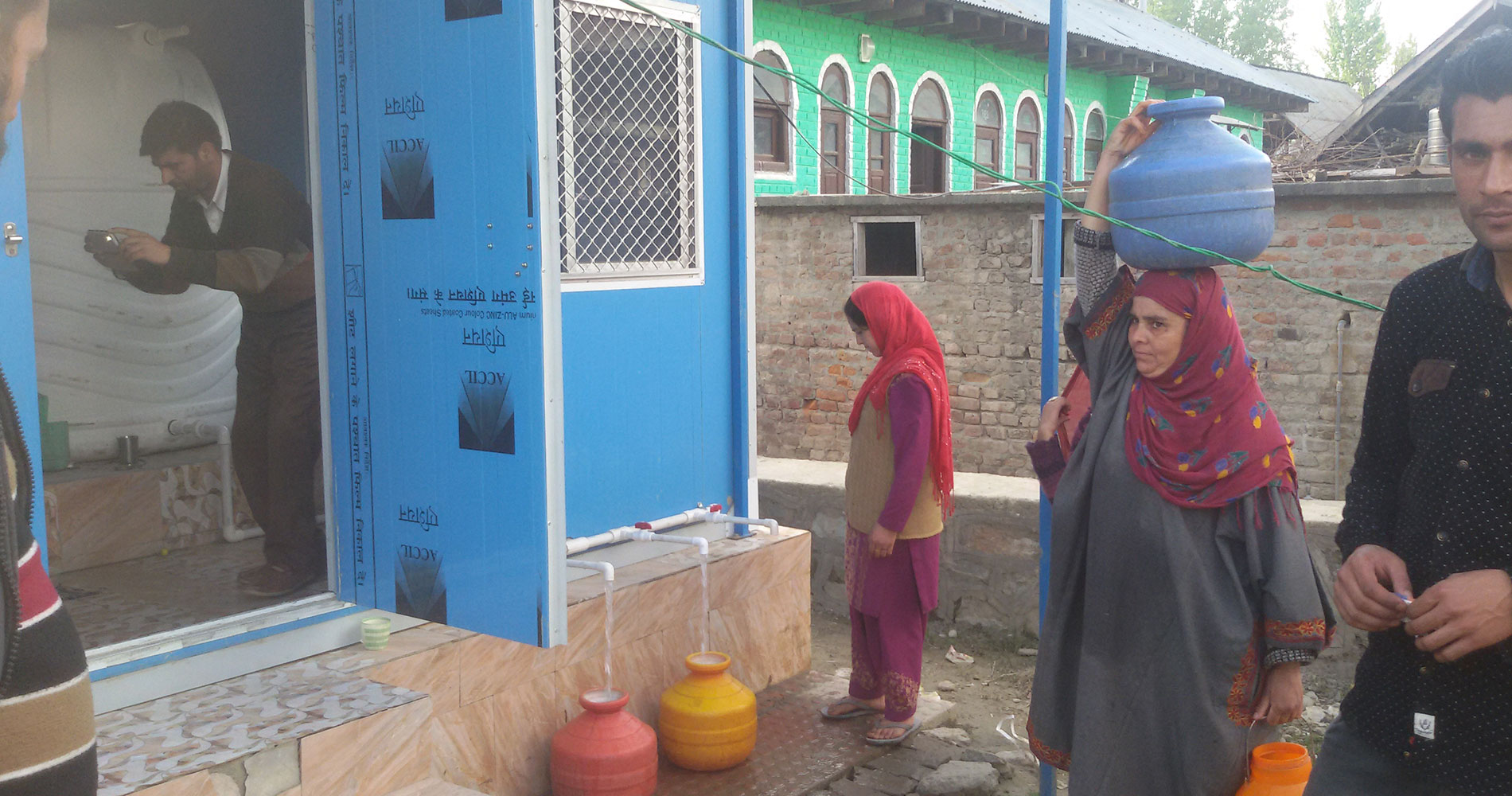 Women collecting water at a Kashmir relief site