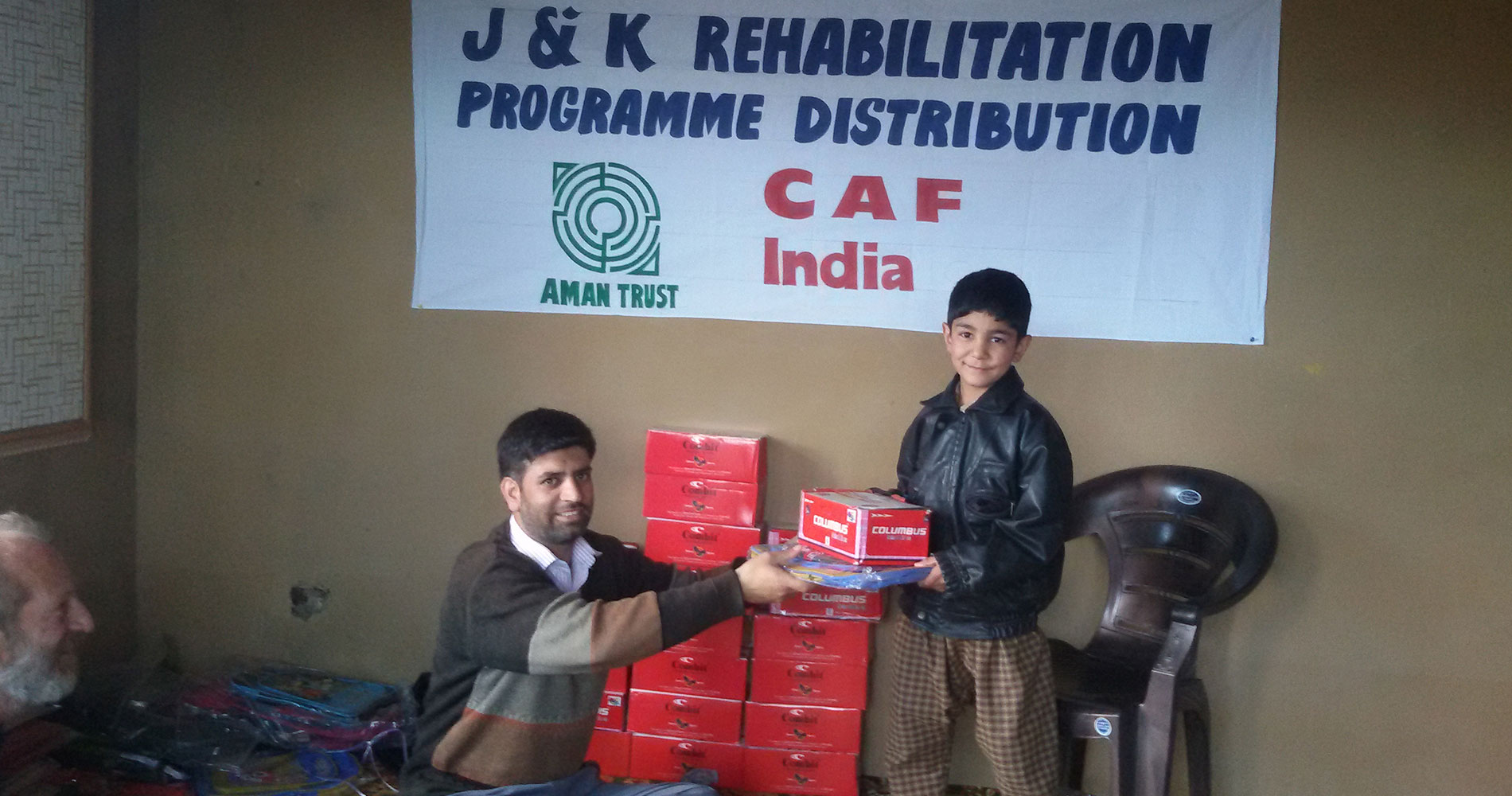 J&K Rehabilitation Programme — distributing supplies to a young beneficiary